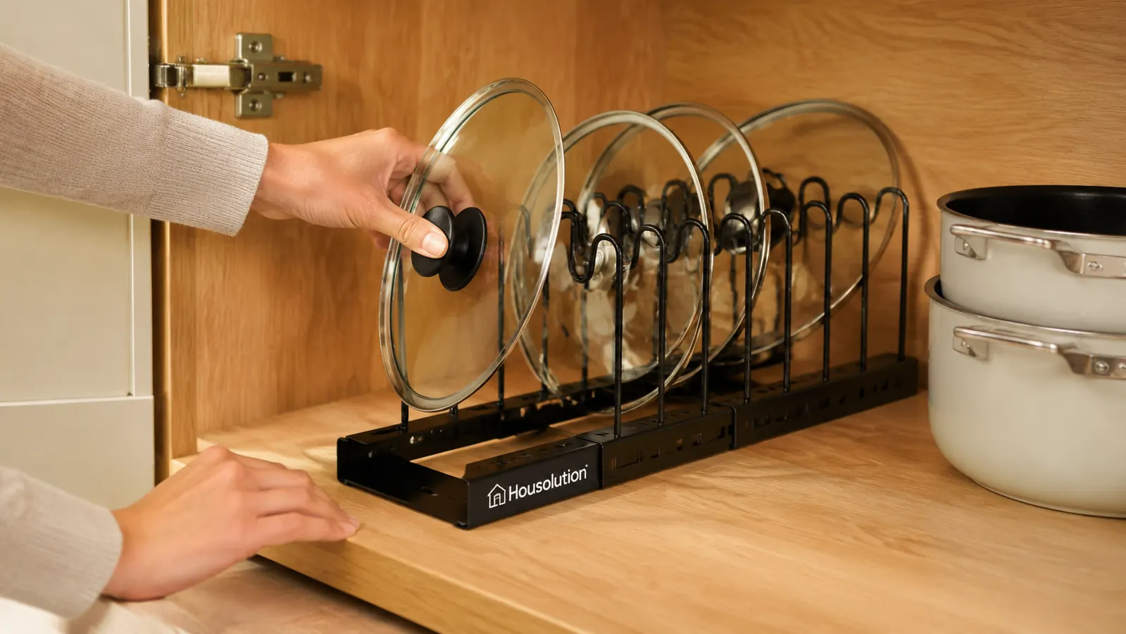 A woman's hand sliding a saucepan lid into an upright slot on the pot lid organizer rack
