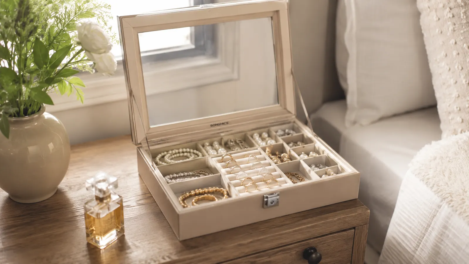 The finished SONGMICS jewelry box open on a dresser top, necklaces, rings, and earrings all visible and separated under the glass lid